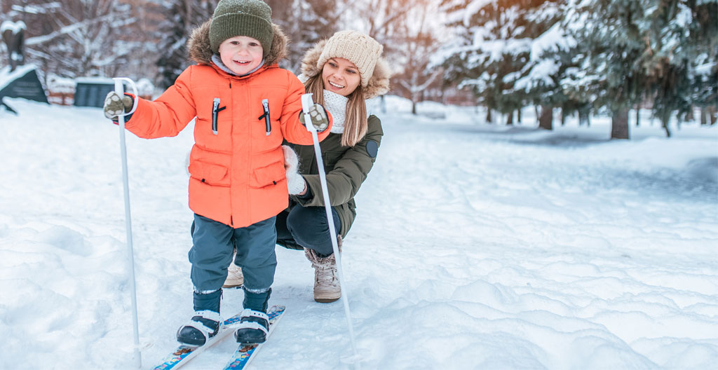 Gros plan sur les mains d'un adulte attachant avec soin les boucles d'une chaussure de ski pour enfant, focus sur les détails du matériel moderne